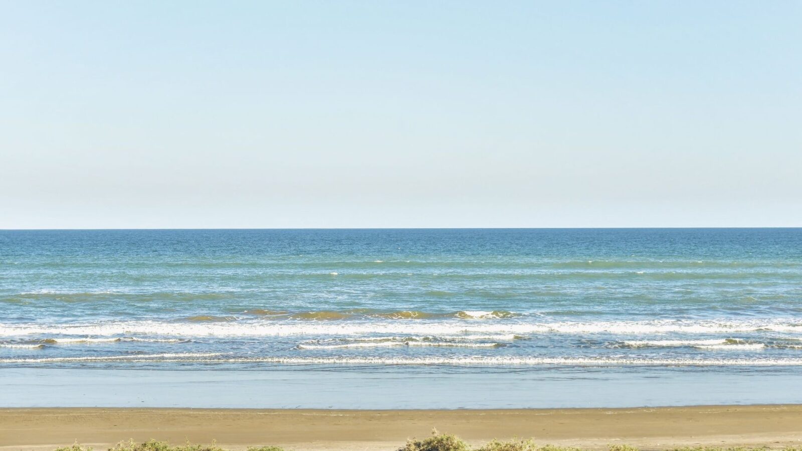 Ruhiger Sandstrand mit sanften Wellen am Meer als Sinnbild für eine Silvesterreise