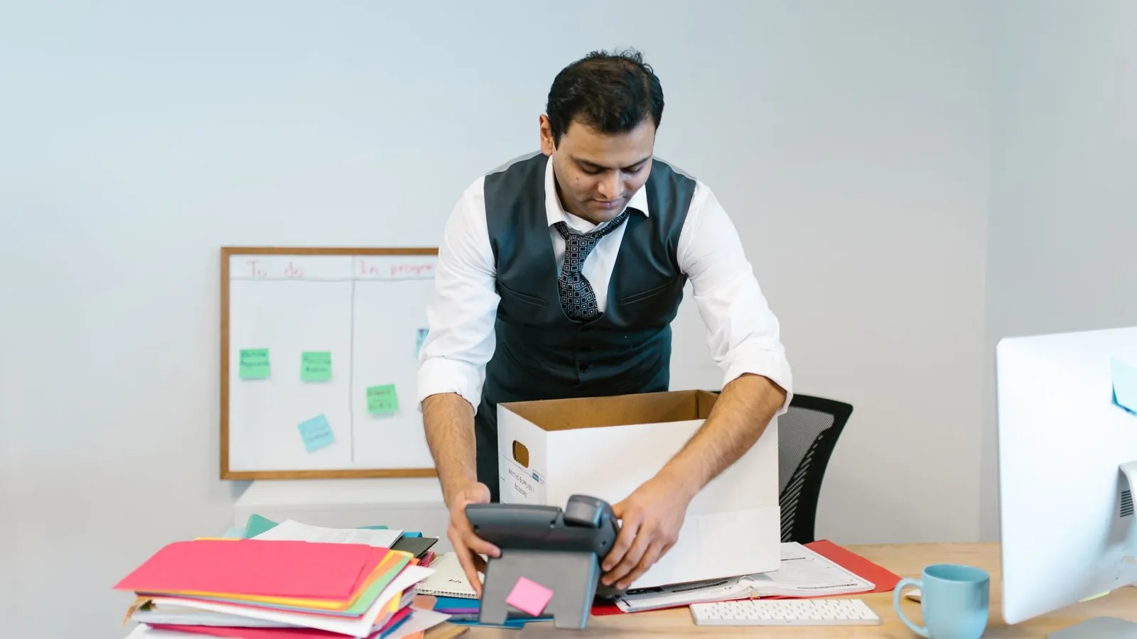 Mann packt seinen Bueroschreibtisch in eine Kiste nach einer Kuendigung des Arbeitsverhaeltnisses