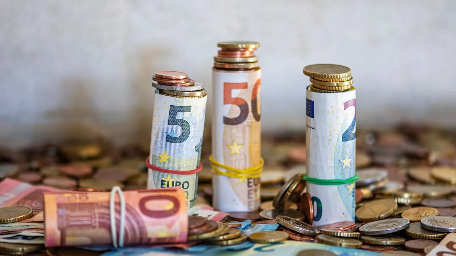 Gerollte Euro-Geldscheine und Muenzen als Symbol fuer die Rueckzahlung der Mietkaution