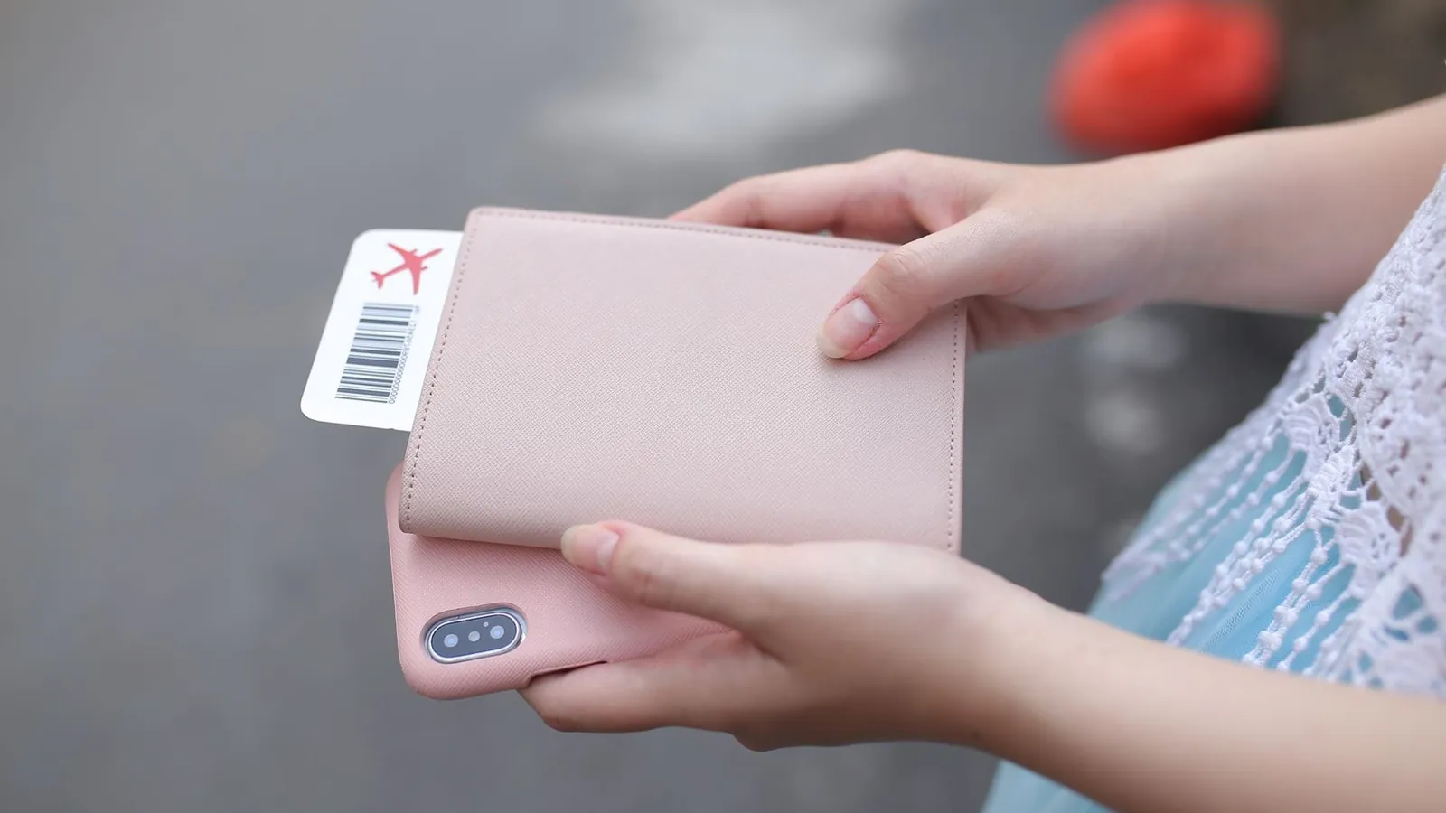 Person haelt eine Passhuelle mit Bordkarte in der Hand vor einer Reise
