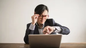 Person schaut besorgt auf die Uhr am Laptop als Symbol fuer dringenden Bedarf an einem vorlaeufigen Ausweisdokument
