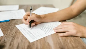 Person fuellt ein Antragsformular fuer den Wohnberechtigungsschein am Schreibtisch aus