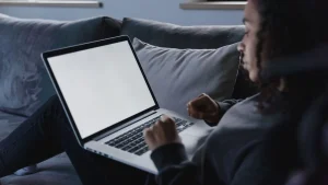 Person wartet vor einem Laptop-Bildschirm waehrend ein Windows 11 Update installiert wird